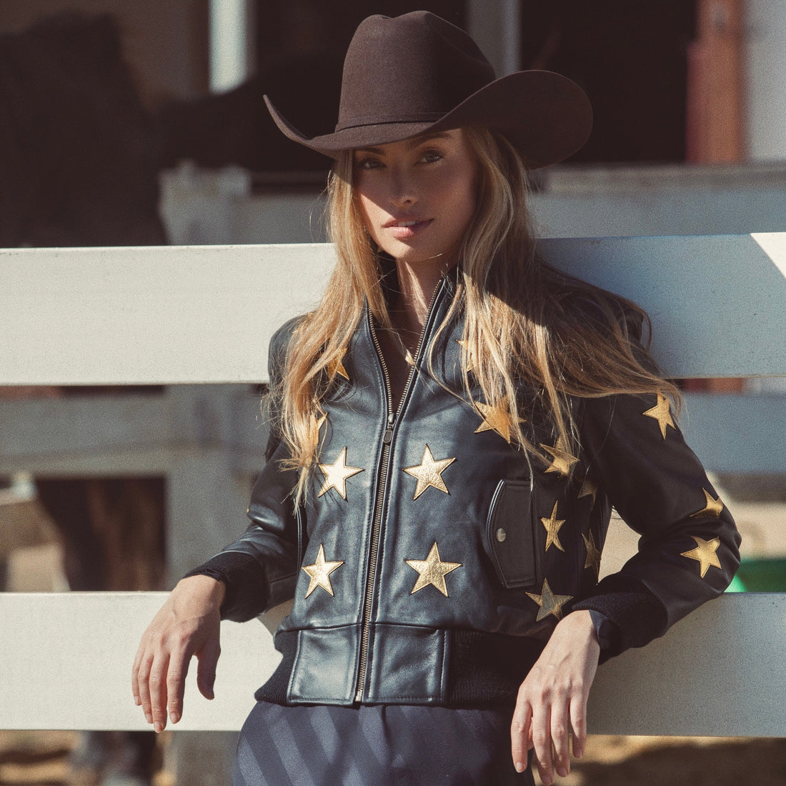 A woman wearing a black bomber jacket with metallic gold stars