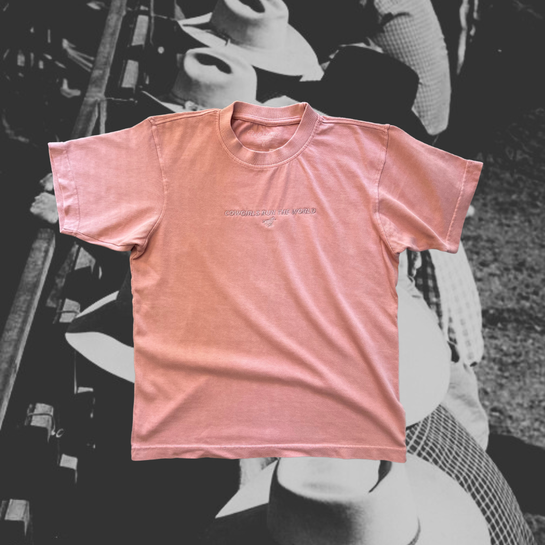 salmon colored tshirt with 'cowgirls run the world' embroidery on the front