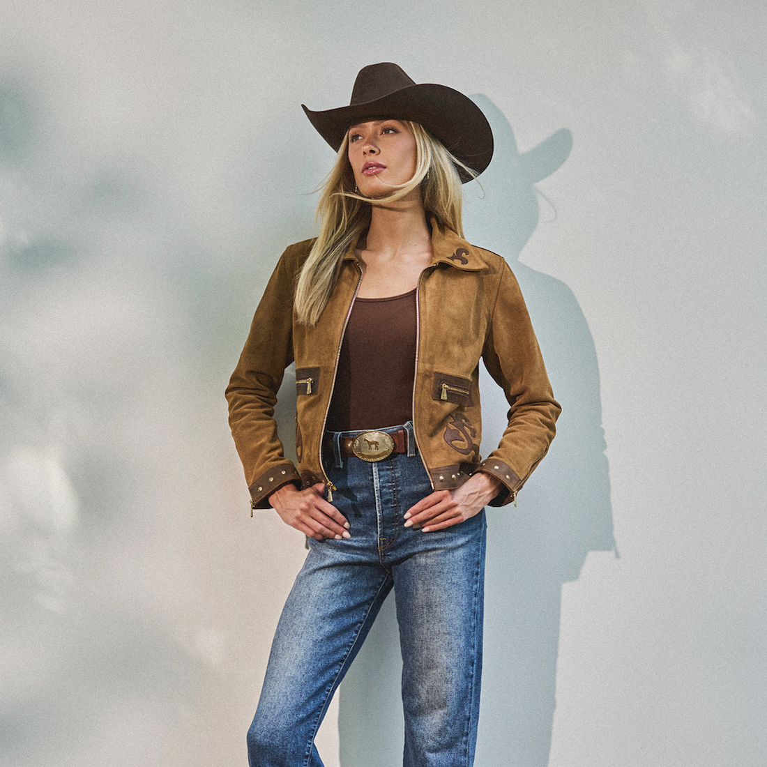 Woman wearing cowboy hat, blue jeans and a brown embroidered jacket by Western & Co
