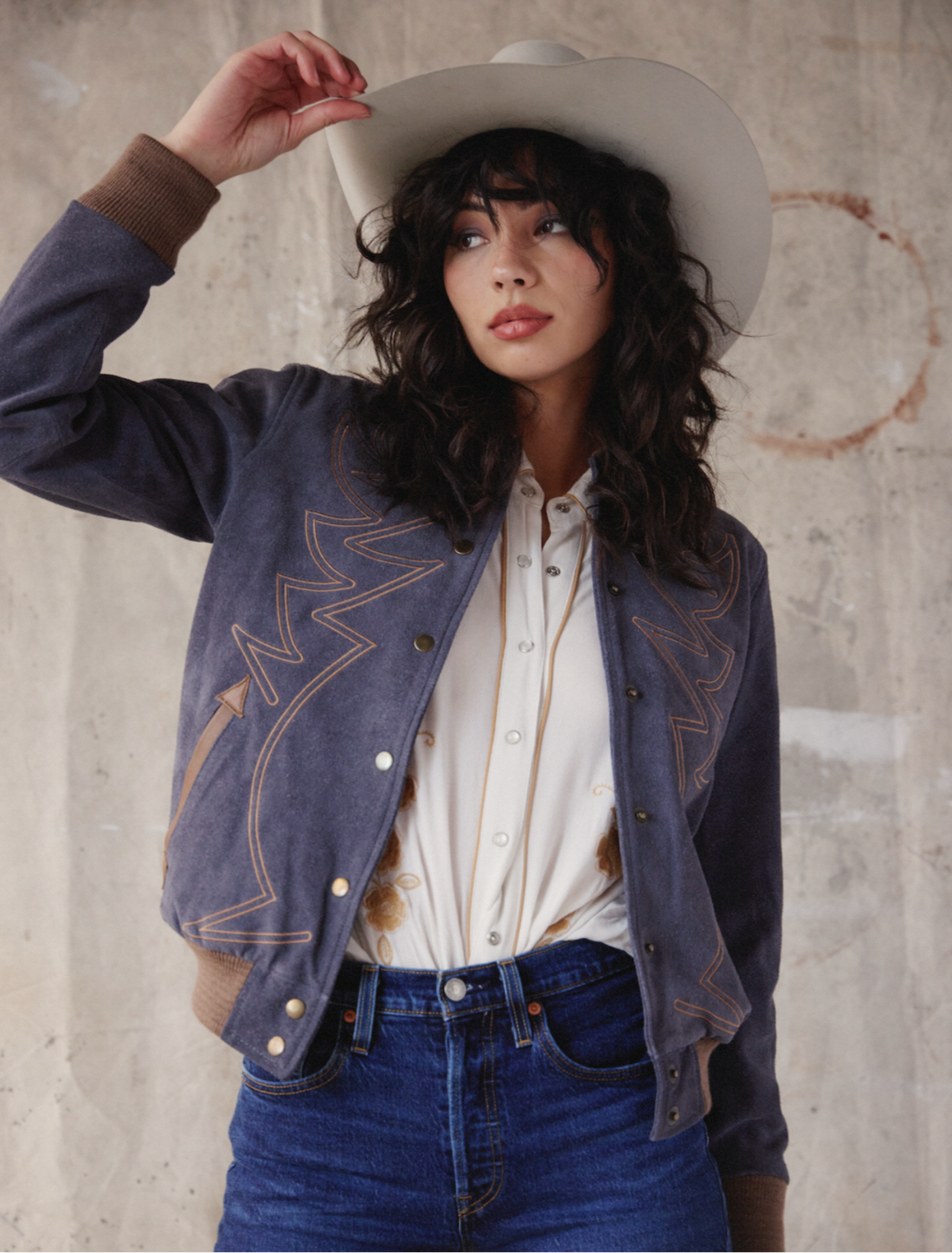 Woman wearing a denim bomber jacket that's embroidered