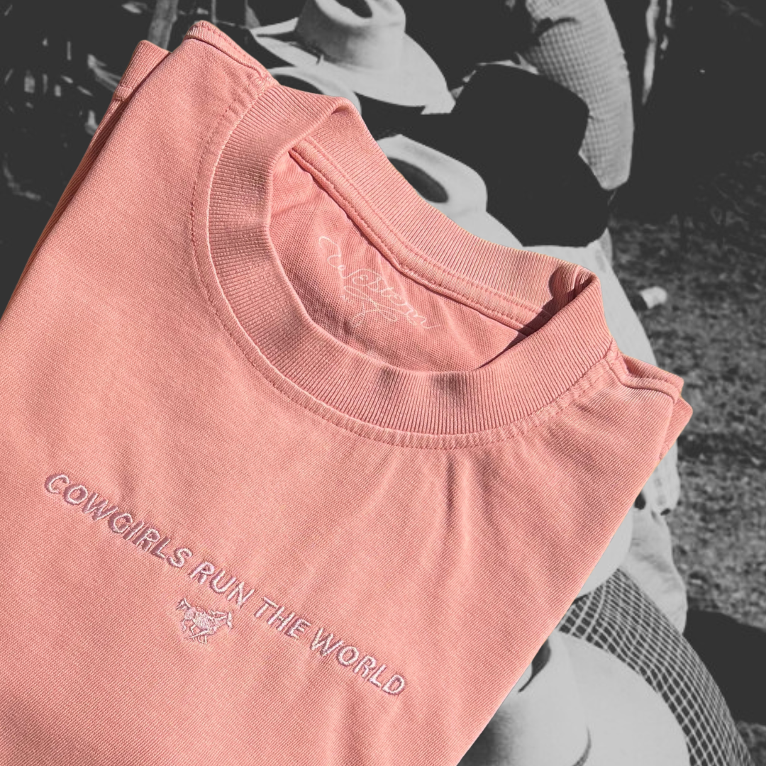 salmon colored tshirt with 'cowgirls run the world' embroidery on the front