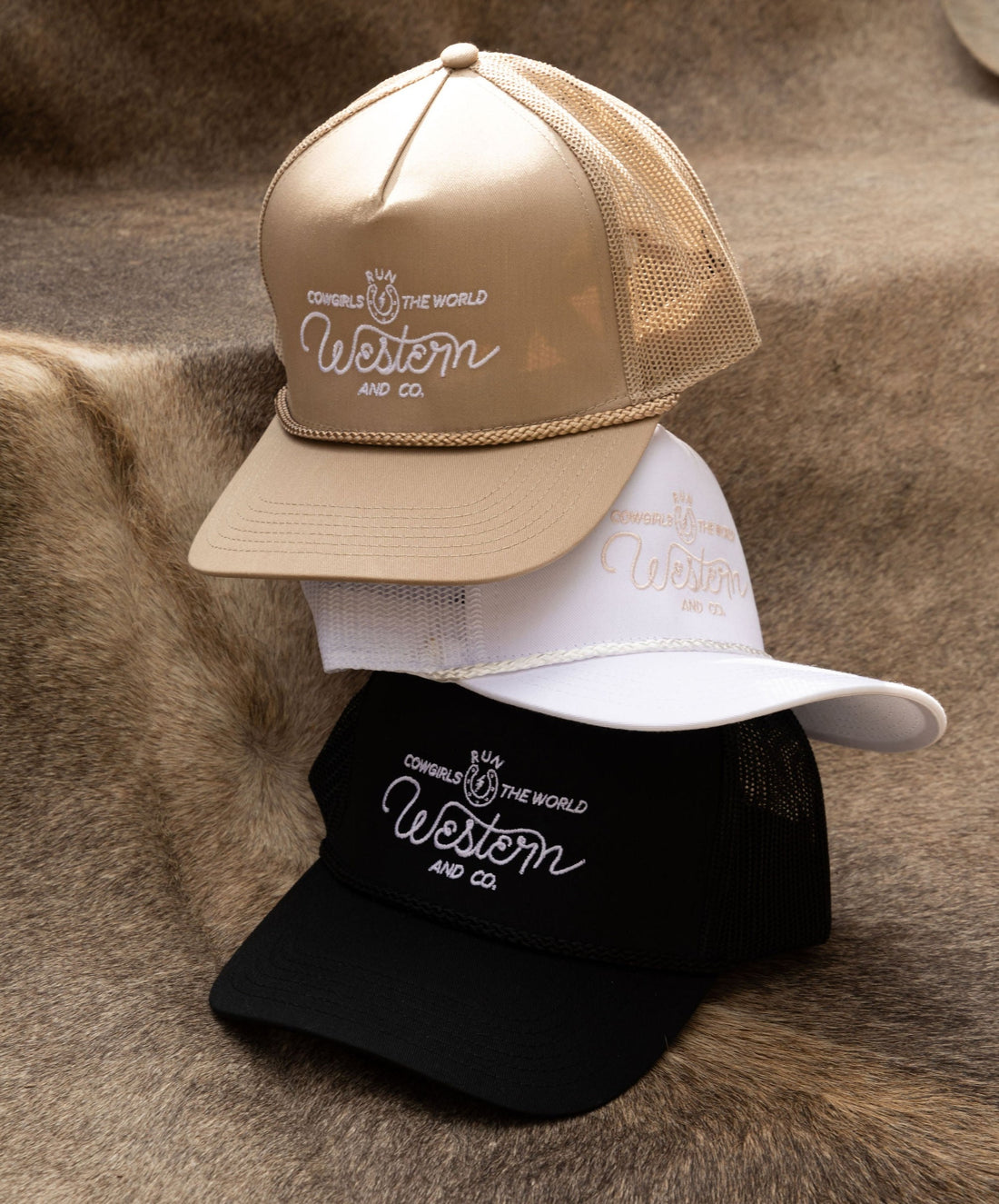 A collection of snapback hats in black, white, beige, and  colors displayed on a surface with Western and Co logo