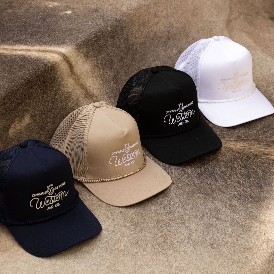 A collection of snapback hats in black, white, beige, and  colors displayed on a surface with Western and Co logo