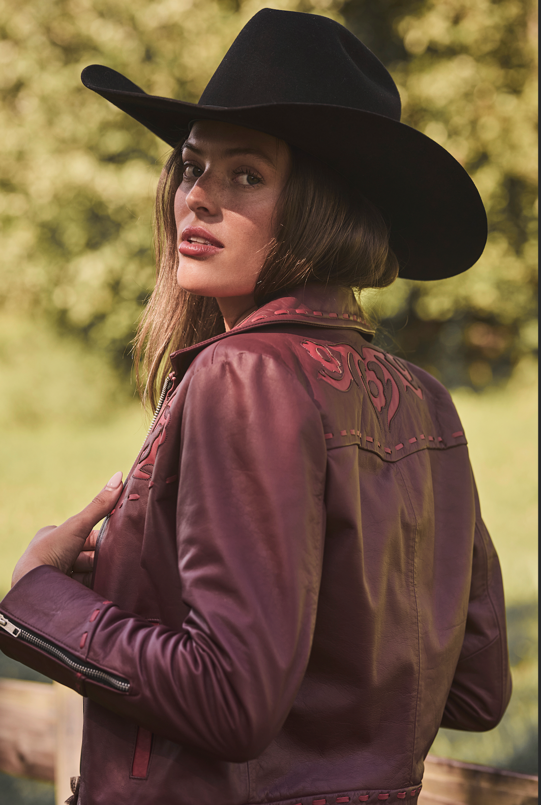 Woman in a cowboy hat wearing embroidered sangria jacket by Western & Co standing outdoors