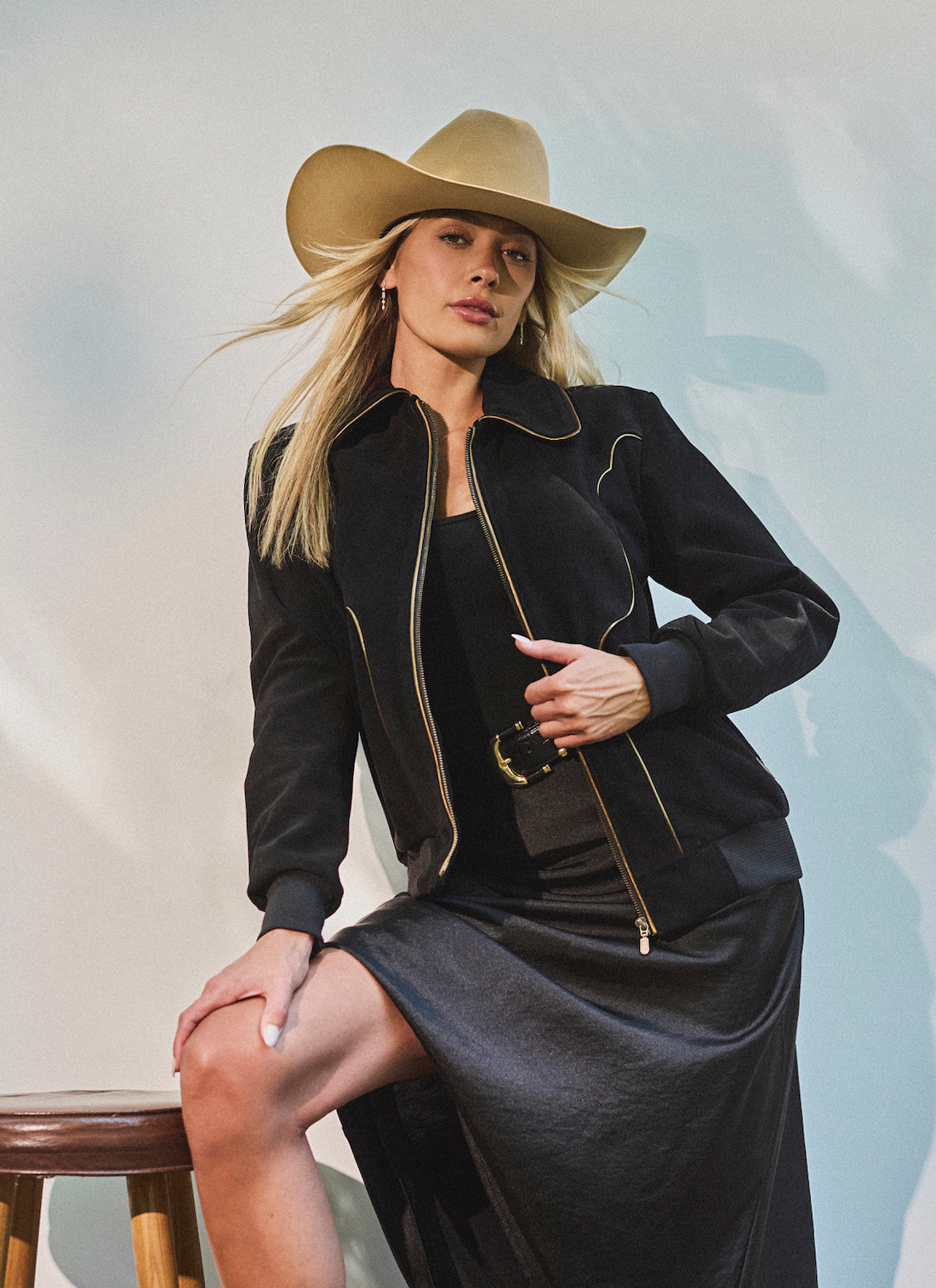 Woman in cowboy hat and black bomber jacket by Western & Co against a light background 